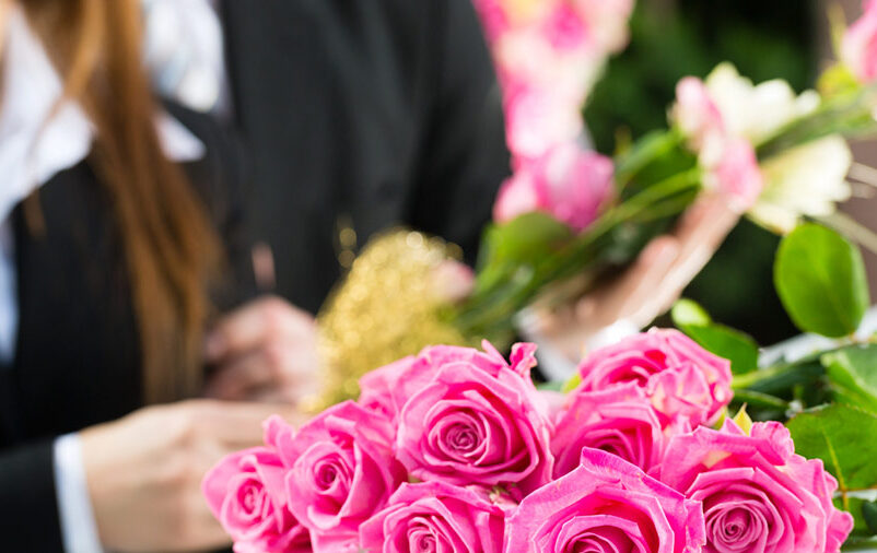 Na imagem vemos uma flor na mão de uma pessoa que conta com um serviço de apoio fúnebre.