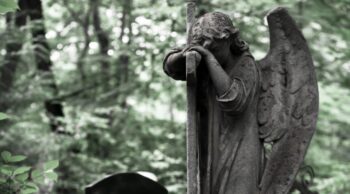 Escultura antiga de um anjo em um jardim, mostrando um exemplo de arte tumular.