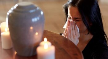 Mulher em luto pela perda do seu ente querido que foi cremado, descobrindo o que é cinerário.