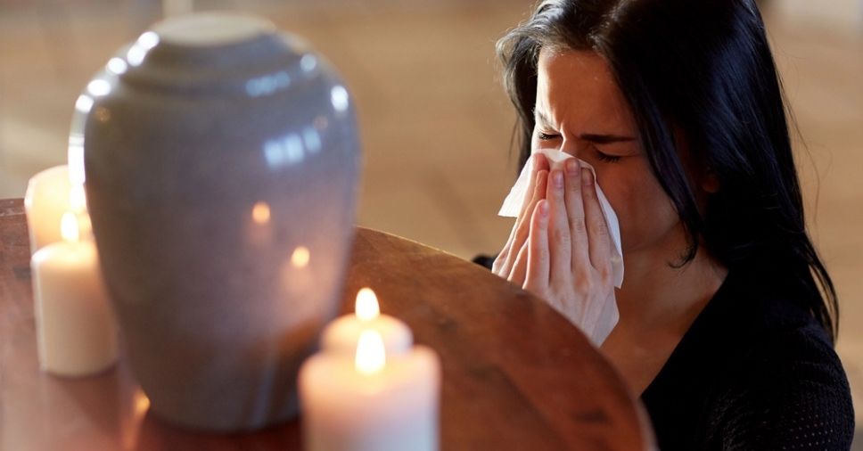Mulher em luto pela perda do seu ente querido que foi cremado, descobrindo o que é cinerário.