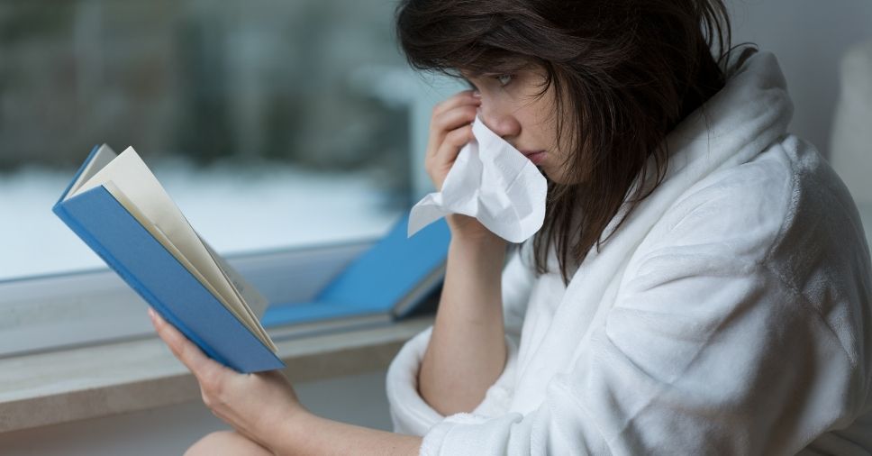 Mulher chora enquanto lê um livro, mostrando a dor dos personagens de livros mortos.