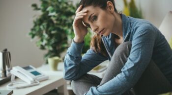 Mulher sentada com expressão de profunda tristeza e angústia em um luto silencioso.