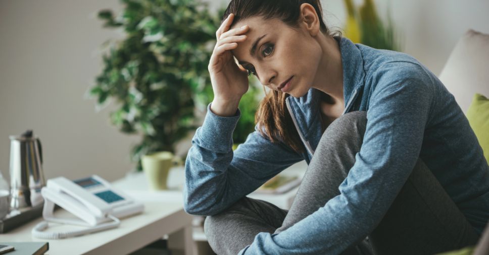 Mulher sentada com expressão de profunda tristeza e angústia em um luto silencioso.