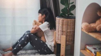 Foto de perfil de criança com pelúcia em momento de terapia pós-luto na infância e introspecção.