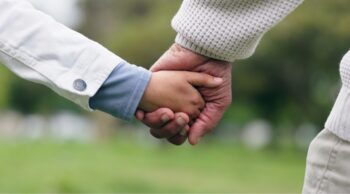 Mãos dadas entre adulto e criança simbolizam o apoio da assistência funerária familiar.