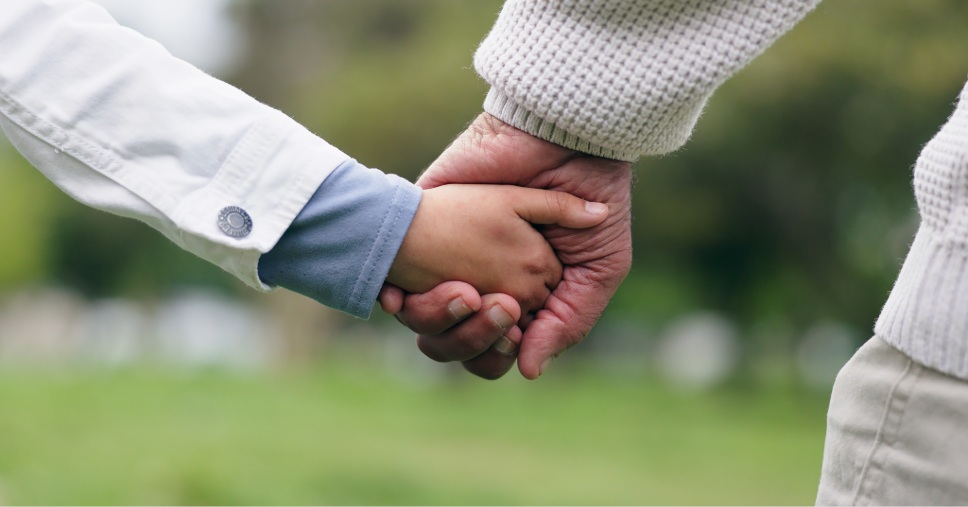 Mãos dadas entre adulto e criança simbolizam o apoio da assistência funerária familiar.